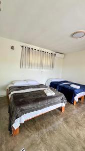 two beds in a room with a window at Vila Arcanjo - Gabriel Chalet in Santana do Riacho +17 photos