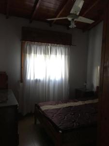 ein Schlafzimmer mit einem Bett und einem Fenster mit einem weißen Vorhang in der Unterkunft Casa San Francisco in Mar del Tuyú