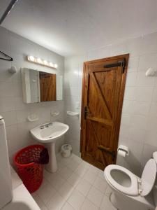 ein Badezimmer mit Toilette und Waschbecken und einer Holztür in der Unterkunft Casa Familiar in La Cumbrecita + 20 Fotos