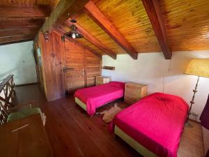 2 Betten in einem Zimmer mit roter Bettwäsche in der Unterkunft Casa Familiar in La Cumbrecita