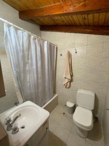 ein Badezimmer mit einer weißen Toilette und einem Waschbecken in der Unterkunft Casa Familiar in La Cumbrecita