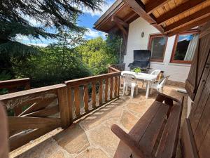eine Terrasse mit einer Bank und einem Tisch und Stühlen in der Unterkunft Casa Familiar in La Cumbrecita
