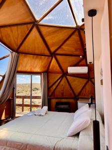 ein Bett in einem Zimmer mit einem großen Fenster in der Unterkunft Secreto Sierras Domos Boutique con Jacuzzi y Desayuno in Aiguá