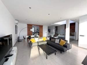 ein Wohnzimmer mit einem schwarzen Sofa und gelben Kissen in der Unterkunft Casa Blanca - Villa à Teguise avec piscine privée in Teguise