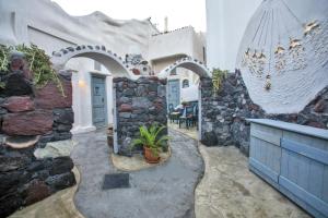 a house with a stone wall and a patio at Αura Cave in Fira