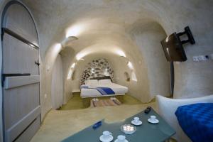 a bedroom with a bed and a table in a room at Αura Cave in Fira +60 photos