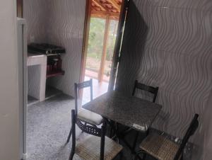 a table and chairs in a room with a wall at Chalé alto valinhos in Itamonte