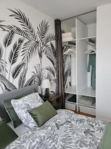 una camera con letto e un murale di palme di Les voiliers a Courseulles-sur-Mer