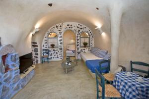 um quarto de hotel com uma cama, uma mesa e cadeiras em Αura Cave em Fira