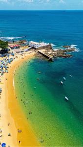 a beach with people and umbrellas and the ocean at Loft Salvador in Salvador