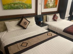 two beds in a room with paintings on the wall at Hoan Kiem Old Quarter Hotel Alley 22 Hang Voi in Hanoi