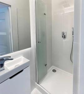 a white bathroom with a shower and a sink at Apartament Lubicz Dolny in Lubicz