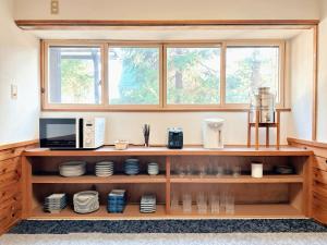 a kitchen with a shelf with plates and a microwave at The Echoland in Hakuba