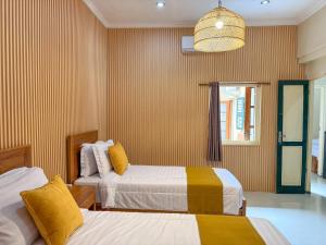 ein Hotelzimmer mit zwei Betten und einem Kronleuchter in der Unterkunft Spacious 5 bedroom Javanese Home near Taman Sari Jogja in Yogyakarta