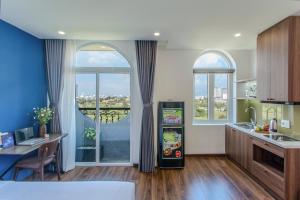 a kitchen with a refrigerator and a table and windows at Fusia Hotel & Apartment in Danang