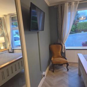 a room with a chair and a television on a wall at Salmon island view in Dromineer