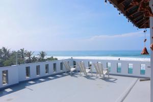 a row of chairs on a balcony overlooking the beach at Shehara Sun Surf Lodge in Midigama