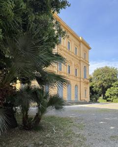 ein großes gelbes Gebäude mit einer Palme davor in der Unterkunft Ars in Villa in Livorno