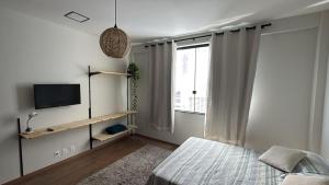 a bedroom with a bed and a tv and a window at Loft Salvador in Salvador