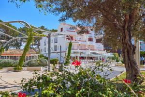 a large white building with a tree and red flowers at Nura Houses Magaluf Apartment in Magaluf