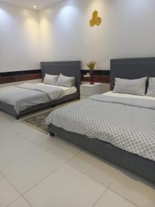twee bedden in een kamer met witte vloeren bij إستراحة الريف in Kalbā