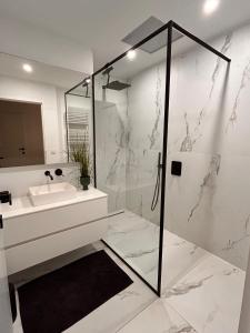 ein weißes Badezimmer mit Waschbecken und Dusche in der Unterkunft Zoute74 - Luxury Penthouse in Knokke-Heist