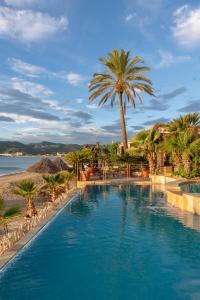 Una gran piscina con palmeras y una playa. en Mare Hotel, en Savona