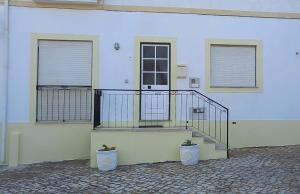 een wit gebouw met een trap en twee planten bij Casa do Omega do Foz in Foz do Arelho