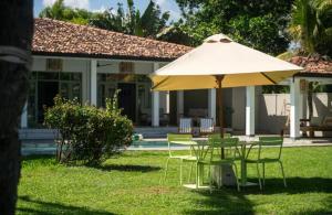 une table et des chaises sous un parasol devant une maison dans l'établissement Villa Elise, à Sinimodera