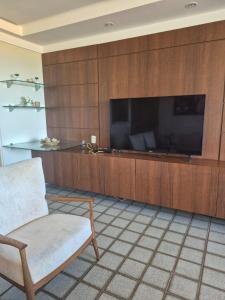 a living room with a large television and a chair at Apartamento Cancún - Praia de Intermares, a 100 metros da Praia in Cabedelo