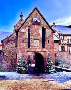 an old brick building with christmas trees in front of it at Gite Les deux belettes in Riquewihr