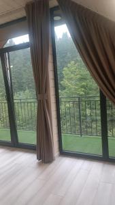 ein leeres Zimmer mit großen Fenstern und einem Balkon in der Unterkunft Спас Резорт in Spas + 8 Fotos
