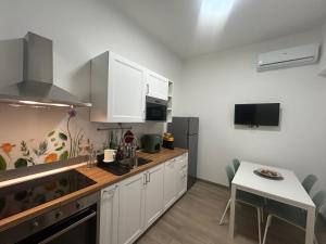 ETNA HOUSE LUXURY con giardino e vasca idromassaggio في لينغواغلوسا: مطبخ بخزائن بيضاء وطاولة صغيرة ومنضدة