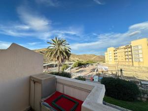 einen Balkon mit Blick auf eine Palme und Gebäude in der Unterkunft Casa Sol y Paz in El Campello