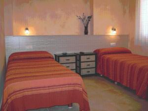 2 Betten in einem Schlafzimmer mit roter und orangefarbener Bettwäsche in der Unterkunft Hostal Valle del Iregua in Albelda de Iregua