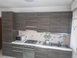 eine Küche mit Holzschränken, Spüle und Mikrowelle in der Unterkunft Papaya58 in San Benedetto del Tronto