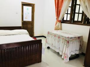 Un dormitorio con dos camas y una mesa y una ventana. en Jayamaha Guest, en Bopitiya