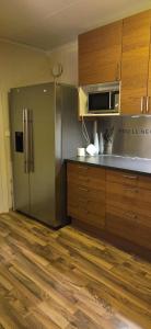 a kitchen with a stainless steel refrigerator and wooden cabinets at Lyngen Ski Apartment in Lyngen