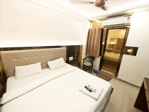 a bedroom with a large white bed and a chair at Hotel The Grend Gauranga Just a min walk from New Delhi Railway Station - Paharganj in Jāmb