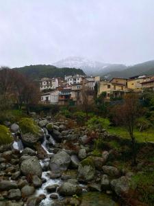 a river with rocks and buildings in the background at las 2 jotas in Guisando