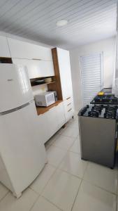 a white kitchen with a stove and a refrigerator at Casa na Guilhermina 500mt da praia in Praia Grande