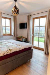 Un dormitorio con una cama y un televisor y ventanas. en Das Nest, en St. Wolfgang