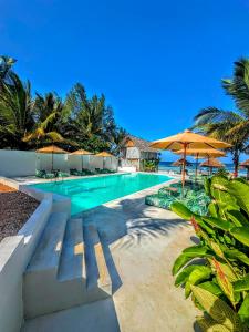a swimming pool with chairs and umbrellas and the ocean at Marea Boutique Hotel in Jambiani