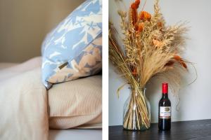 a bottle of wine and a vase with flowers at Gastsuite het Duinroosje met hottub op het privé terras! in Den Burg