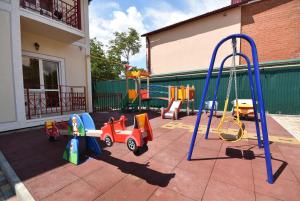 a playground with different types of toys in a yard at Guest House Capri in Kabardinka