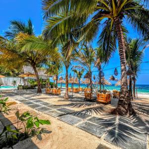 a beach with chairs and palm trees and the ocean at Marea Boutique Hotel in Jambiani