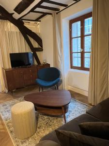 a living room with a couch and a table and a tv at Le Nid Bellifontain - Appartement Confort - Centre in Fontainebleau