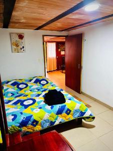 ein Schlafzimmer mit einem Bett mit einer bunten Bettdecke in der Unterkunft Cabaña Campestre Renacer in Paipa + 4 Fotos