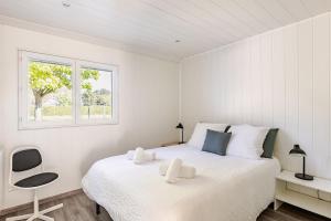 a white bedroom with a bed and a window at Villa, piscine chauffée, aux portes de Lyon in Sainte-Euphémie