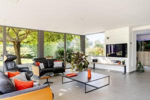 a living room with couches and a table at Villa, piscine chauffée, aux portes de Lyon in Sainte-Euphémie